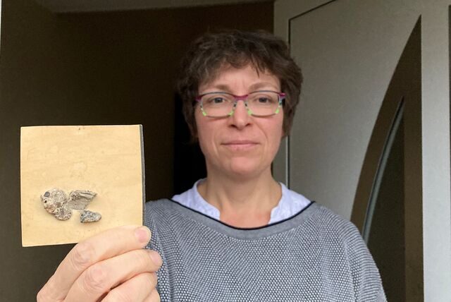 Eine Frau hält in Recklinghausen ein Stück Papier mit aufgeklebten Beton-Bröckchen in der Hand.