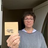 Eine Frau hält in Recklinghausen ein Stück Papier mit aufgeklebten Beton-Bröckchen in der Hand.
