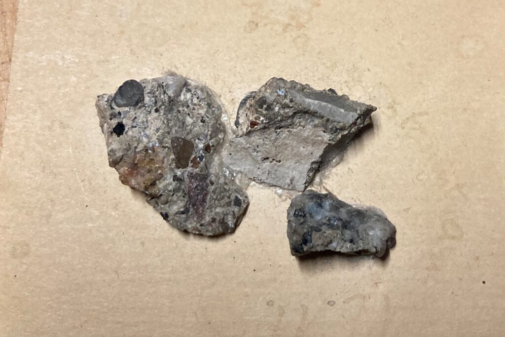 Drei kleine Betonbrocken liegen auf einem Stück Papier. Drei kleine Betonbrocken liegen auf einem Stück Papier.