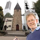 Pfarrer Reinhard Vehring vor einer Montage der Türme der vier katholischen Kirchen in Oer-Erkenschwick.