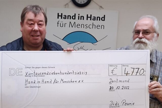 Detlef „Didi“ Pourie (links) steht mit einem Scheck über 4770 Euro neben Rüdiger Engler vom Verein „Hand in Hand für Menschen“.