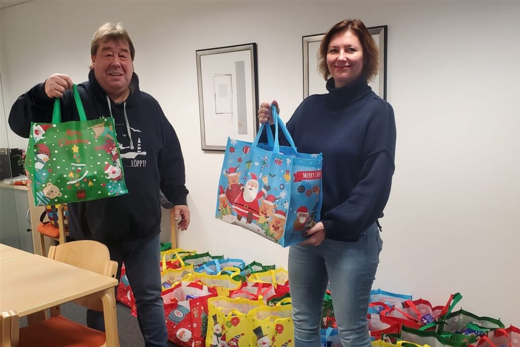 Didi Pourie aus Waltrop und Caritas-Mitarbeiterin Magdalena Wegener stehen vor einer Reihe von Einkaufstüten mit Spenden.