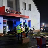 Feuerwehrkräfte stehen vor der Sparkassenfiliale am Bachackerweg, nachdem sie den Brand gelöscht haben.