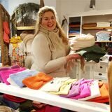 Eine junge Frau hält Schals in den Händen, im Vordergrund liegen bunte Stirnbänder.