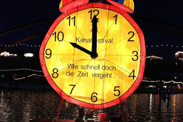 Das Bild zeigt eine gelb leuchtende Uhr. Das Foto wurde während des Kanalfestivals in Datteln aufgenommen.