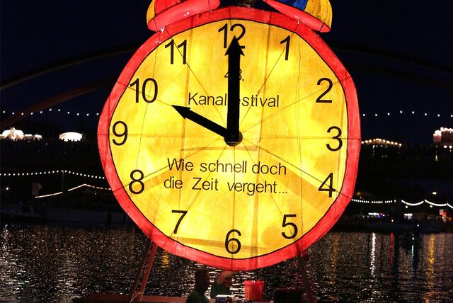 Das Bild zeigt eine gelb leuchtende Uhr. Das Foto wurde während des Kanalfestivals in Datteln aufgenommen.