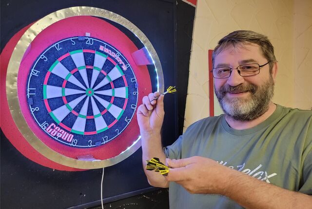 Hobby-Darter Frank Royek vor einer Dartscheibe.