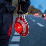 Ein Verkehrspolizist hält eine Kelle mit dem Aufdruck „Halt Polizei“ in der Hand.