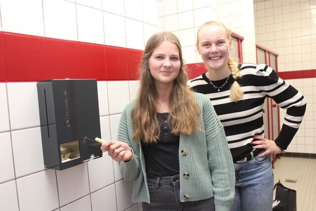 Rebecca Winterberg (re.) und Charlotta Coumans von der Schülervertretung am Theodor-Heuss-Gymnasium in Waltrop stehen neben einem Periodenprodukte-Spender in einer der Schultoiletten.