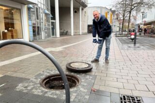 Ein Mann, der einen Gullideckel aus einer Vertiefung gezogen hat.