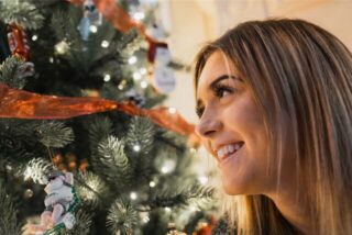 Eine Frau freut sich über beim Anblick eines Weihnachtsbaumes.