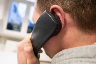 Das Symbolbild zeigt einen Mann mit einem Telefonhörer am Ohr.