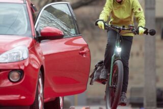 Symbolbild eines Radfahrers, der einer geöffneten Autotür ausweicht.