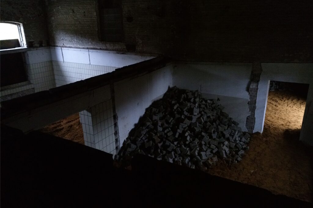 Ein Steinhaufen in einem dunklen Gebäude. Auf dem Boden ringsum befindet sich Sand. Ein Steinhaufen in einem dunklen Gebäude. Auf dem Boden ringsum befindet sich Sand.