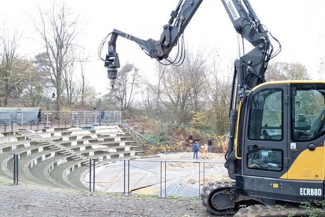 Mit einem Bagger und einem Bohrer wird der Boden rund um das Amphitheater im Bürgerpark auf mögliche Kampfmittel aus dem Zweiten Weltkrieg untersucht.