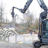 Mit einem Bagger und einem Bohrer wird der Boden rund um das Amphitheater im Bürgerpark auf mögliche Kampfmittel aus dem Zweiten Weltkrieg untersucht.
