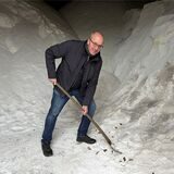 Ein Mann hält in einem Streusalzlager eine Schaufel in der Hand.