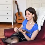 Eine junge Frau hört in ihrer Wohnung Musik.