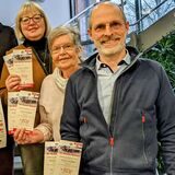 Die Veranstalter des Konzertes halten Plakate und Flyer in die Kamera.