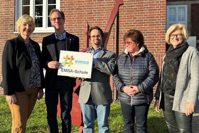 Musikschulleiterin Sabine Fiebig-Fechtner, Sascha Schiefer, EMSA Koordinator für die Musikschule, Robert Fahrun, EMSA Koordinator für das Städtische Gymnasium, Brigitte Rode, Leiterin des Amtes für schulische Bildung und Bärbel Schweers, Rektorin des Gymnasiums, stehen vor dem Schulgebäude in Herten, in dem Musikschule und Gymnasium untergebracht sind.