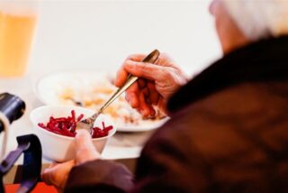 Eine alte Frau hält in ihrer Hand eine Salatschüssel.