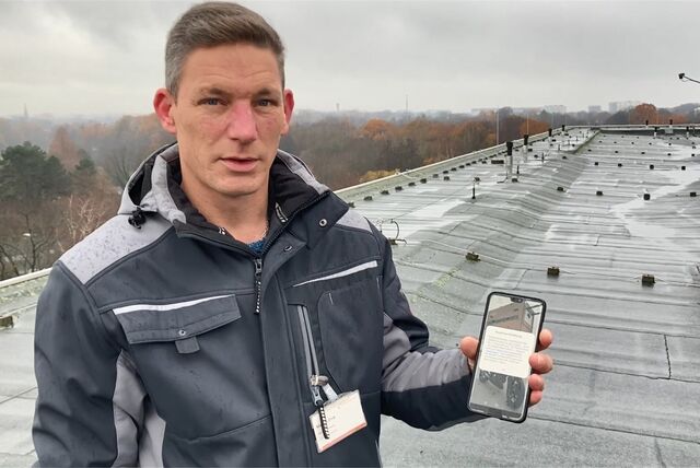Ein Mann mit Handy auf einem Dach