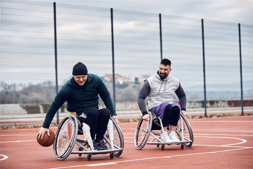 zwei menschen in rollstühlen spielen basketball