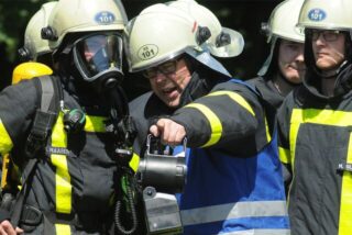 Ein Feuerwehrmann erklärt seinen Kollegen etwas bei einer Übung.
