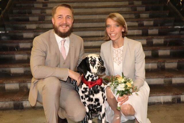 Timo und Franziska hocken zusammen mit Hund Paul vor der Treppe des Dortmunder Standesamtes, wo die beiden gerade geheiratet haben.