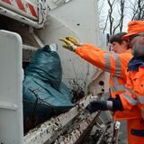 Mitarbeiter des EUV schmeißen Müll in den Abfuhrwagen.