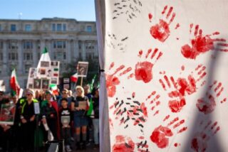 Menschen demonstrieren mit Fahnen und Schildern für die Protestierenden im Iran