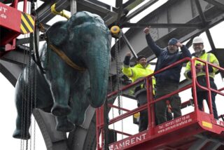 Eine Elefantenskulptur hängt unter einem Stahlbogen