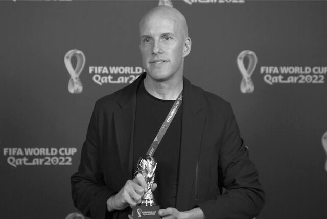 Der US-Sportjournalist Grant Wahl zeigt eine Miniatur des WM-Pokals.