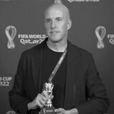 Der US-Sportjournalist Grant Wahl zeigt eine Miniatur des WM-Pokals.
