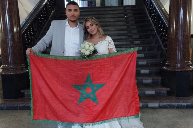 Elmekki und Maryam halten stolz eine marokkanische Flagge hoch. Das Paar hat gleich zwei Gründe zum Feiern.
