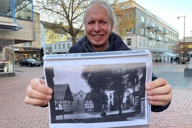 Stadtarchivar Thomas Jasper steht am Simon-Cohen-Platz, wo bis 1938 die Synagoge stand. Er hält eine Schwarz-Weiß-Fotografie in die Kamera. Auf dem Bild ist das Gebäude noch zu erkennen.