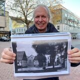 Stadtarchivar Thomas Jasper steht am Simon-Cohen-Platz, wo bis 1938 die Synagoge stand. Er hält eine Schwarz-Weiß-Fotografie in die Kamera. Auf dem Bild ist das Gebäude noch zu erkennen.