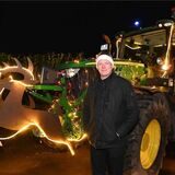 Landwirt Michael Sprenger steht vor einem beleuchteten Trecker.