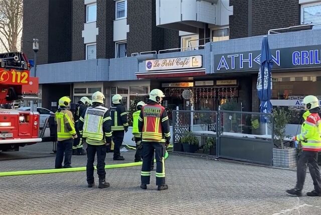 Einsatzkräfte der Hertener Feuerwehr stehen auf dem Marktplatz vor einem Wohn- und Geschäftshaus.