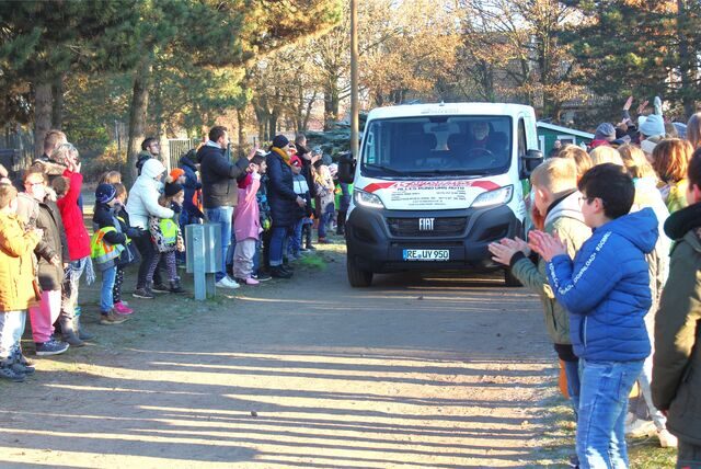 Ein gesponserter Bulli rollt auf den Schulhof der Schule Oberwiese in Waltrop, links und rechts stehen Schüler und klatschen.