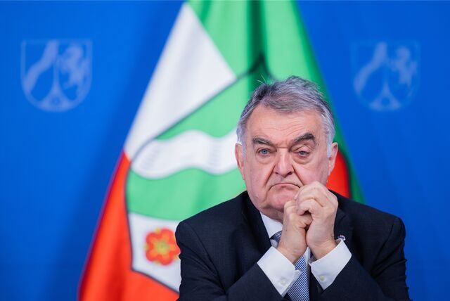 Innenminister Herbert Reul sitzt bei einer Pressekonferenz vor der Flagge des Landes Nordrhein-Westfalen.