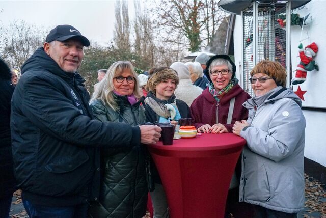 Ein Mann und vier Frauen stehen winterlich gekleidet an einem Bistrotisch. Auf dem Tisch stehen Tassen.