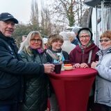 Ein Mann und vier Frauen stehen winterlich gekleidet an einem Bistrotisch. Auf dem Tisch stehen Tassen.