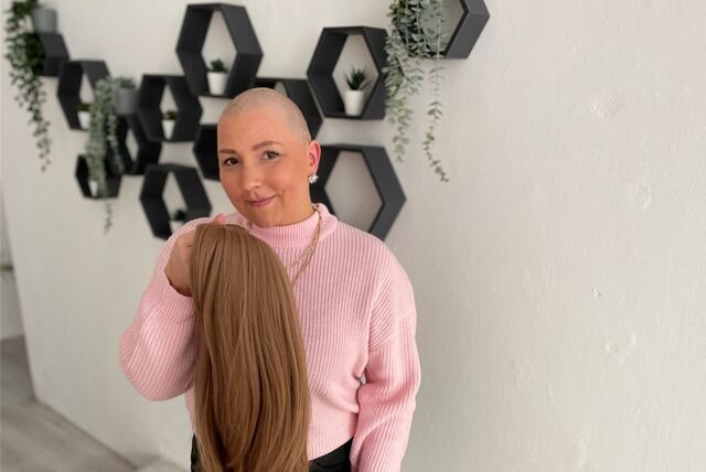 Rebecka Brandt hält ihre Perücke in der Hand.