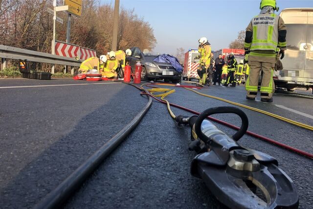 Im Vordergrund liegt eine Rettungsschere der Feuerwehr Waltrop, im Hintergrund Unfall- und Feuerwehrfahrzeuge.