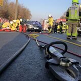 Im Vordergrund liegt eine Rettungsschere der Feuerwehr Waltrop, im Hintergrund Unfall- und Feuerwehrfahrzeuge.