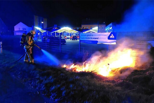 Ein Feuerwehrmann löscht nahe dem Autohaus Winkelheide in Waltrop einen kleinen Flächenbrand.