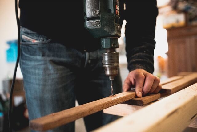 mann bohrt in holz