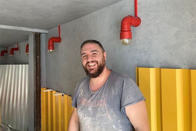 Ein lachender Mann steht vor einer grauen Wand in einer Gastronomie in Recklinghausen.
