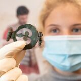 Jule Materlik, Restauratorin, zeigt einen römischen Pferdegeschirranhänger. Das Stück stammt aus archäologischen Ausgrabungen auf dem Gelände der Varusschlacht im Osnabrücker Land – Museum und Park Kalkriese.